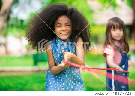 Happy children playing tug of war in the park. Happy children playing tug of war in the park. 48377723