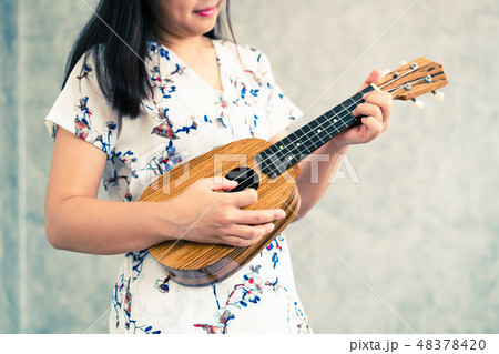 Happy woman musician playing ukulele in studio. 48378420