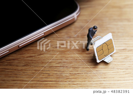スマートホンからSIMカードを抜き取り運ぶ男性 48382391