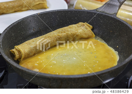 The process of cooking Japanese omelet roll.  48386429