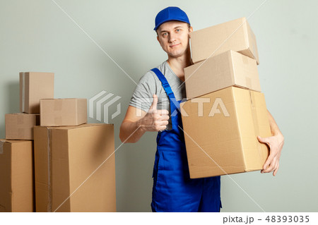 Day moving. Delivery of goods from shopping in the online store. The loader or courier smiles and 48393035