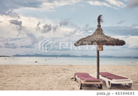 Umbrella and a pair of sunbeds on a beach. Umbrella and a pair of sunbeds on a beach. 48394693