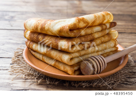 Thin pancakes stacked on a wooden background.  48395450