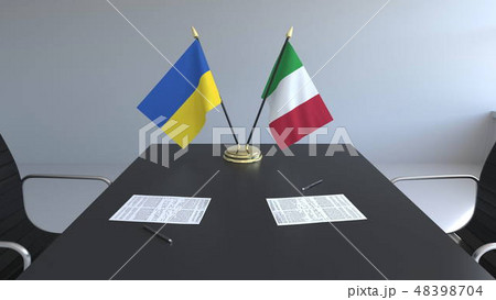 Flags of Ukraine and Italy and papers on the table. Negotiations and signing an international Flags of Ukraine and Italy and papers on the table. Negotiations and signing an international 48398704