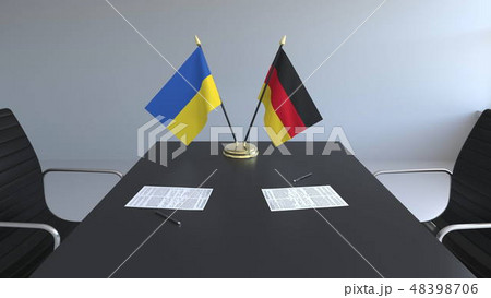 Flags of Ukraine and Germany and papers on the table. Negotiations and signing an international Flags of Ukraine and Germany and papers on the table. Negotiations and signing an international 48398706