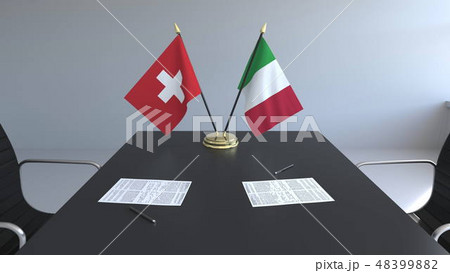 Flags of Switzerland and Italy and papers on the table. Negotiations and signing an international 48399882