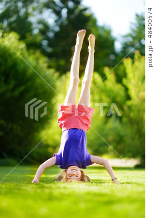 Happy young child playing head over heels on green grass in spring park 48400574