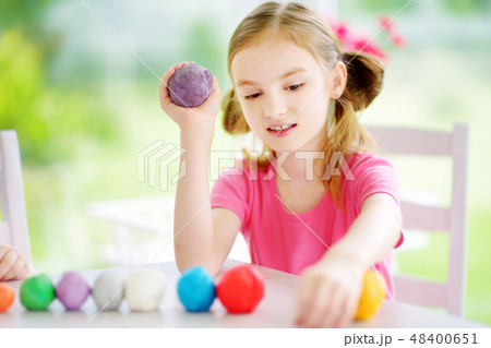 Cute little girl having fun with modeling clay at a daycare. Creative kid molding at home. Cute little girl having fun with modeling clay at a daycare. Creative kid molding at home. 48400651