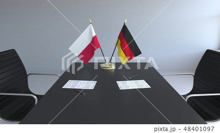 Flags of Poland and Germany and papers on the table. Negotiations and signing an international Flags of Poland and Germany and papers on the table. Negotiations and signing an international 48401097