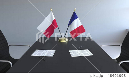 Flags of Poland and France and papers on the table. Negotiations and signing an international Flags of Poland and France and papers on the table. Negotiations and signing an international 48401098