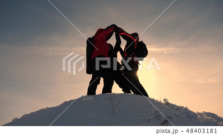 team work and victory. Tourists come to top of snowy hill and rejoice at victory against backdrop of 48403181