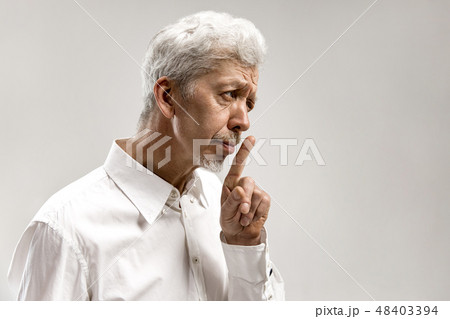 Serious frightened male keeps fore finger on lips 48403394