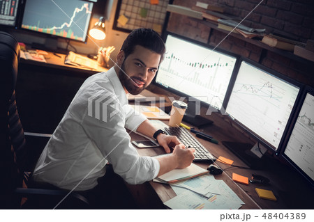 Young male trader at office work concept sitting looking camera happy Young male trader at office work concept sitting looking camera happy 48404389
