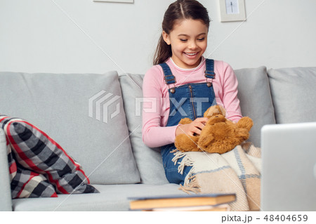 Little girl at home sitting playing with teddy bear joyful 48404659