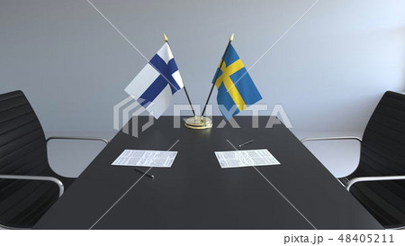Flags of Finland and Sweden and papers on the table. Negotiations and signing an international Flags of Finland and Sweden and papers on the table. Negotiations and signing an international 48405211