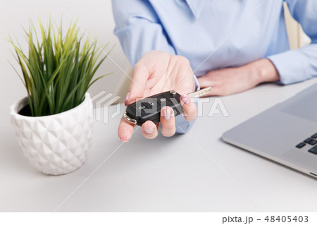 Yong pretty woman holding keys and giving it to the customer. Contract of buing a car. Yong pretty woman holding keys and giving it to the customer. Contract of buing a car. 48405403