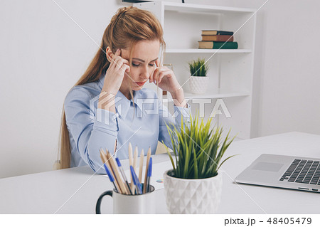 Young office girl sitting at her workplace feeling bad. Woman has a headache. Young office girl sitting at her workplace feeling bad. Woman has a headache. 48405479
