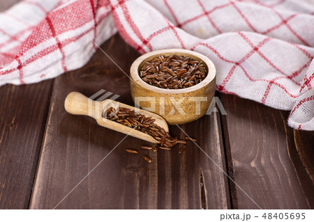 Raw red rice on brown wood Raw red rice on brown wood 48405695
