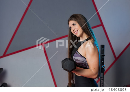 Very beautiful girl trains biceps with dumbbells 48408093