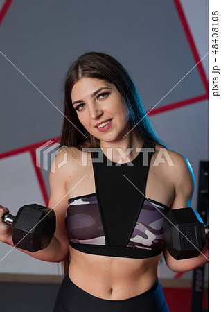 Very beautiful girl trains biceps with dumbbells 48408108