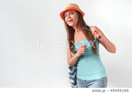 Summer mood. Woman in hat standing studio isolated on white with beach bag holding sunglasses Summer mood. Woman in hat standing studio isolated on white with beach bag holding sunglasses 48409166