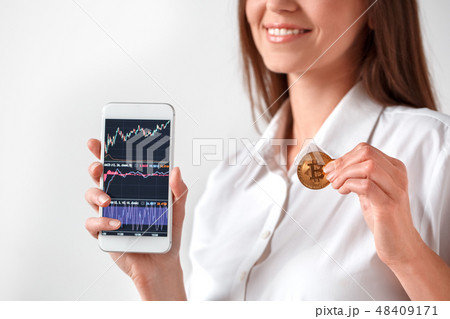 Cryptocurrency. Woman standing isolated on white showing screen of smartphone with statistics Cryptocurrency. Woman standing isolated on white showing screen of smartphone with statistics 48409171