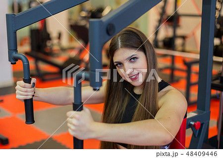 Beautiful girl at the gym exercising on trainers. Beautiful girl at the gym exercising on trainers. 48409446