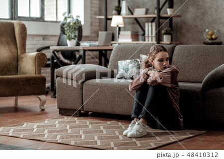 Teenage girl feeling discouraged and depressed sitting at home alone 48410312
