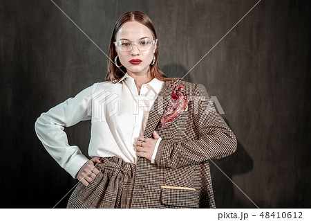 Serious young woman demonstrating her stylish jacket Serious young woman demonstrating her stylish jacket 48410612
