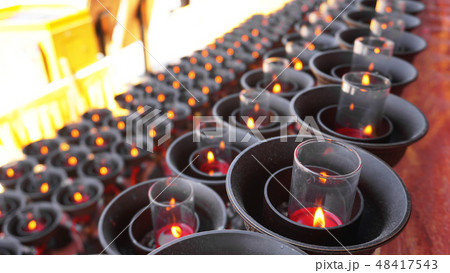 Burning big red candles in Buddhist temple 48417543