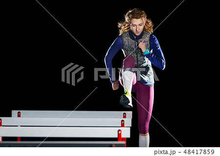 Young female athlete training running with hurdles Young female athlete training running with hurdles 48417859