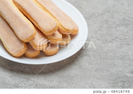 Italian Savoiardi ladyfingers Biscuits in plate on concrete backgound Italian Savoiardi ladyfingers Biscuits in plate on concrete backgound 48418749