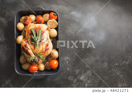 Roasted chicken with potatoes on black table. Roasted chicken with potatoes on black table. 48421271