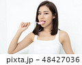 Smiling curly Asian girl  holding and eating candy lollipop on w 48427036