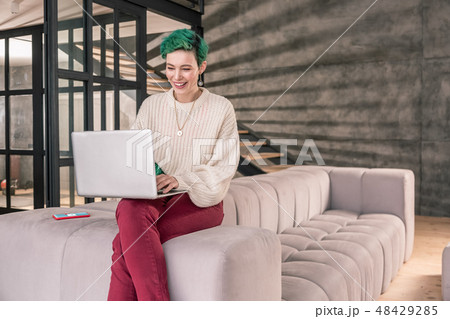 Freelance writer working on her laptop sitting on sofa at home Freelance writer working on her laptop sitting on sofa at home 48429285