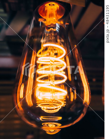 Bright glowing clear glass lamp pear shaped close up. Illumination edison retro lamp dark background Bright glowing clear glass lamp pear shaped close up. Illumination edison retro lamp dark background 48431195