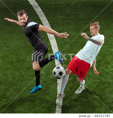 Football players tackling ball over green grass background Football players tackling ball over green grass background 48431785