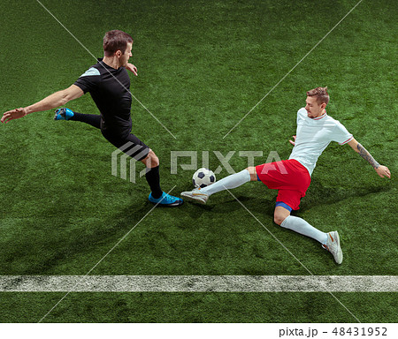 Football players tackling ball over green grass background 48431952