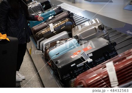 people waiting for luggage on a conveyor belt people waiting for luggage on a conveyor belt 48432563