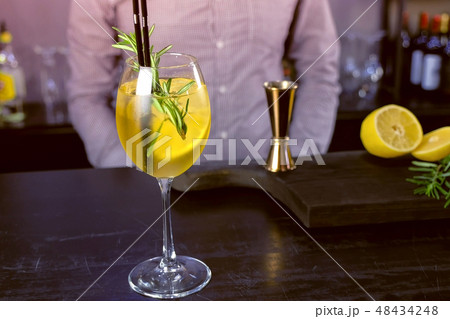 Alcohol cocktail with sparkling wine, ice and liquor , lemon and rosemary in wineglass on bar 48434248