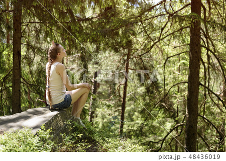 Dreaming beautiful girl sitting on a stone 48436019