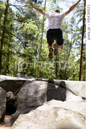 Young man jumps on a rock in a coniferous forest Young man jumps on a rock in a coniferous forest 48436021