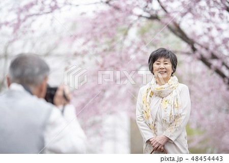 桜の中で写真を撮るシニア夫婦 48454443