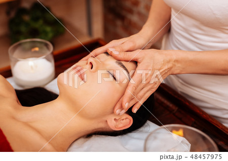 Experienced masseuse in white t-shirt making relaxing massage for face Experienced masseuse in white t-shirt making relaxing massage for face 48457975
