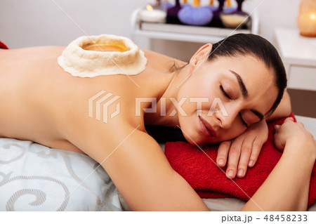 Dark-haired tranquil woman peacefully lying on massage bed Dark-haired tranquil woman peacefully lying on massage bed 48458233