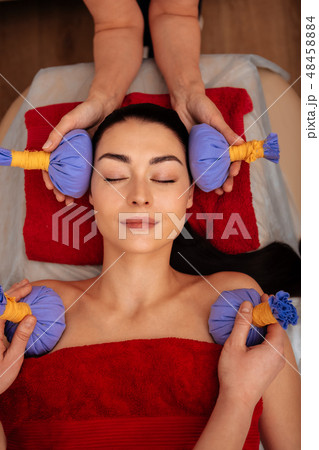 Relaxed peaceful lady feeling great while workers attaching blue bags Relaxed peaceful lady feeling great while workers attaching blue bags 48458884