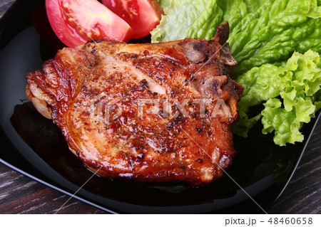 grilled pork chops with tomato, leaves lettuce and ketchup on plate. grilled pork chops with tomato, leaves lettuce and ketchup on plate. 48460658