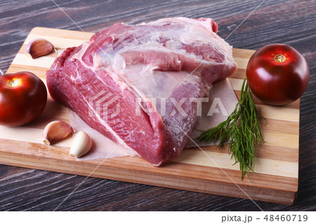 Raw pork steaks on wooden board with herbs, garlic, spices and tomatoes ready for cooking. Selective Raw pork steaks on wooden board with herbs, garlic, spices and tomatoes ready for cooking. Selective 48460719