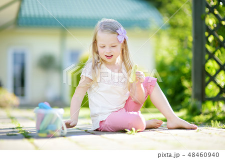 Cute little girl drawing with colorful chalks on a sidewalk. Summer activity for small kids. Cute little girl drawing with colorful chalks on a sidewalk. Summer activity for small kids. 48460940