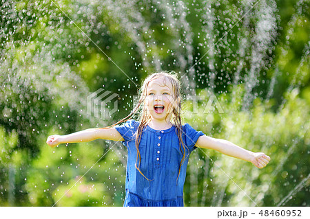 Adorable little girl playing with a sprinkler  48460952